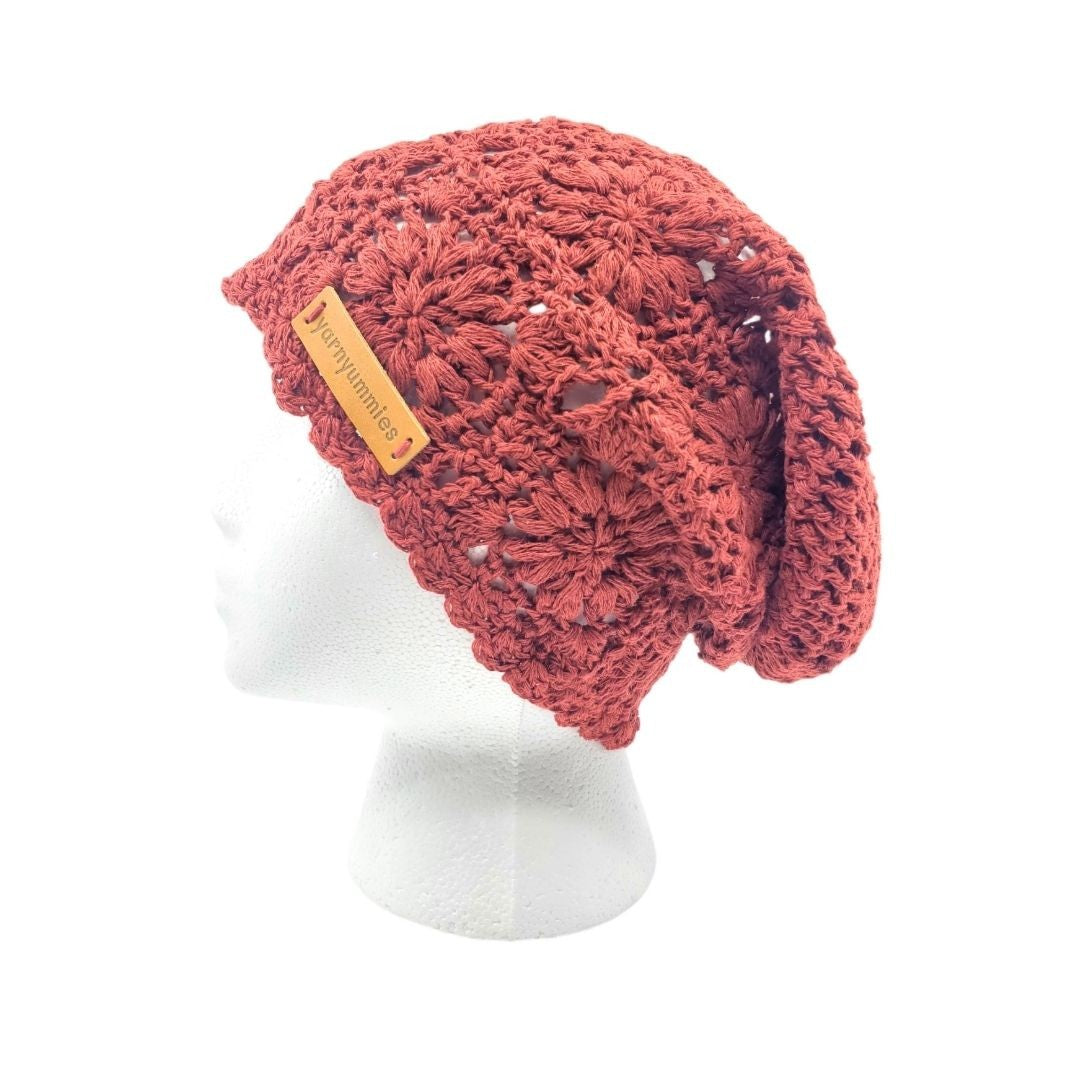 Crocheted red beanie with a brand tag on a white background