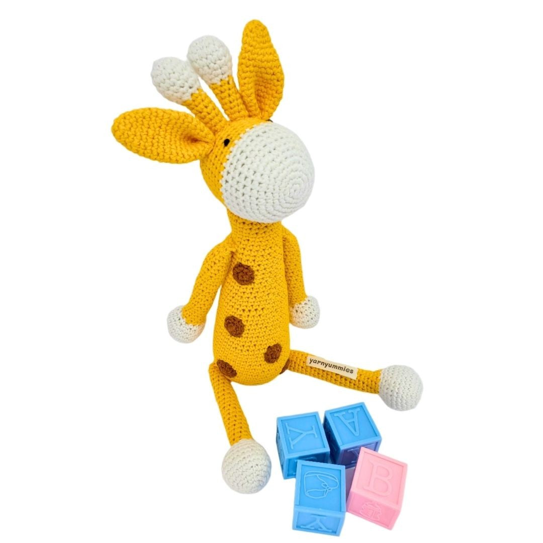 Crocheted toy donkey with colorful blocks on a white background