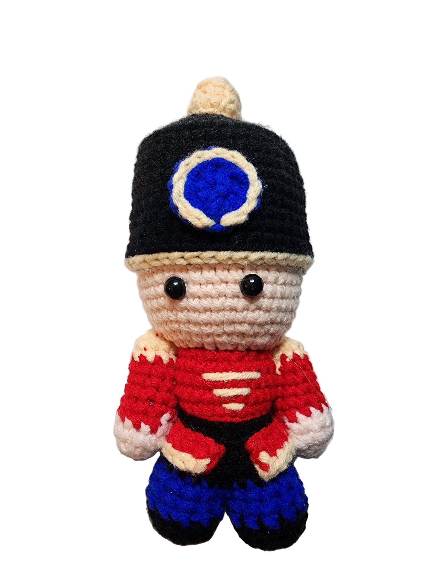 Crocheted toy resembling a character with a black helmet, red scarf, and blue accents on a white background.