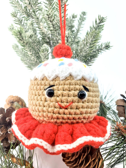 A handmade crochet gingerbread head Christmas tree ornament with a beige body, red collar, and a multicolored cotton yarn hat.