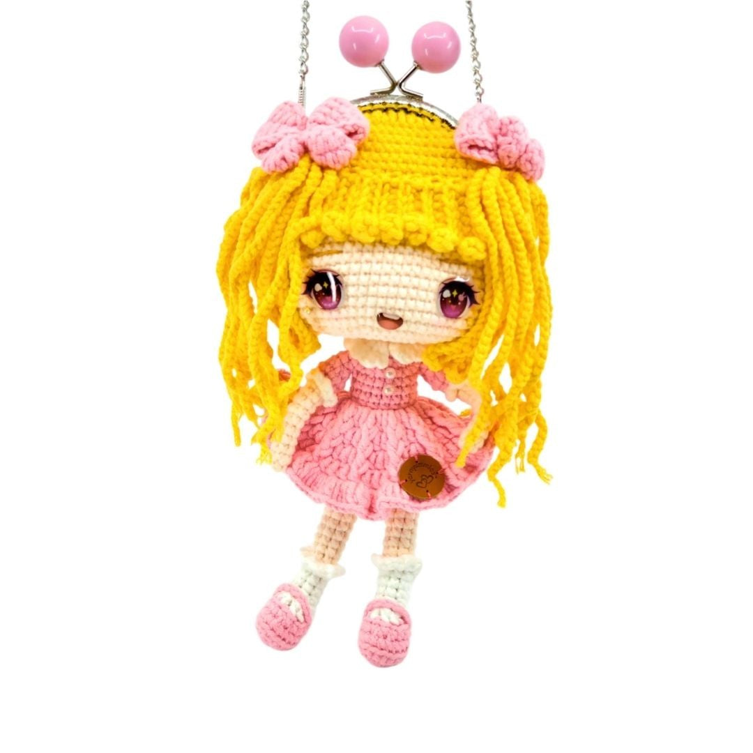 Crocheted doll with yellow hair and pink dress on a white background