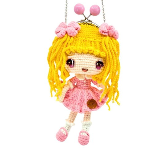Crocheted doll with yellow hair and pink dress on a white background