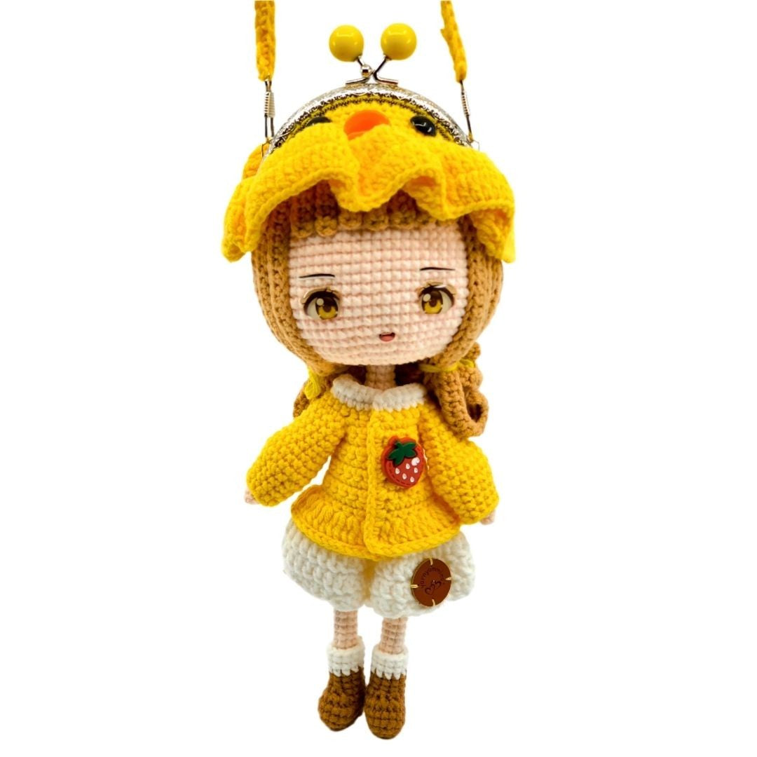 Crocheted doll with yellow outfit and hat on a white background