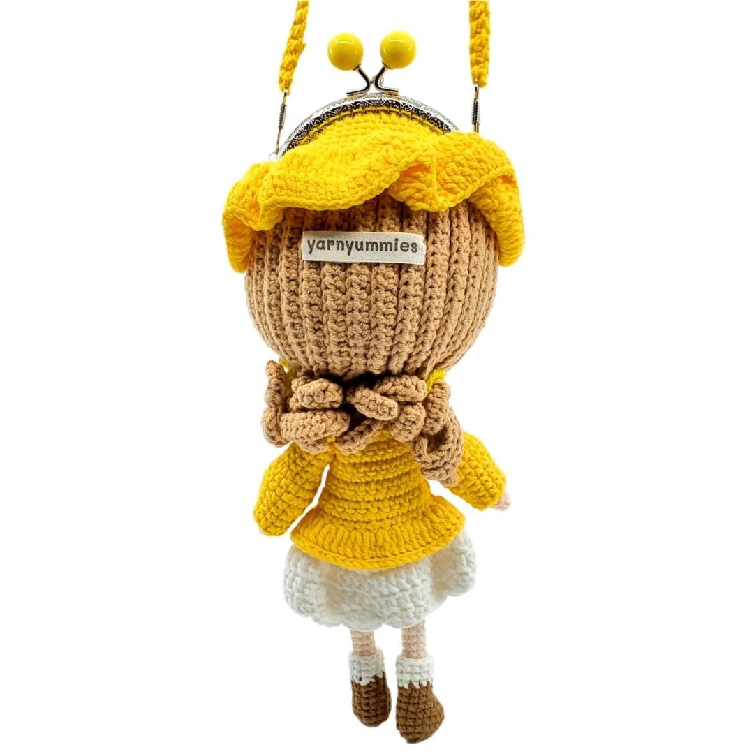 Crocheted doll character with a yellow dress and brown honeycomb head on a white background.