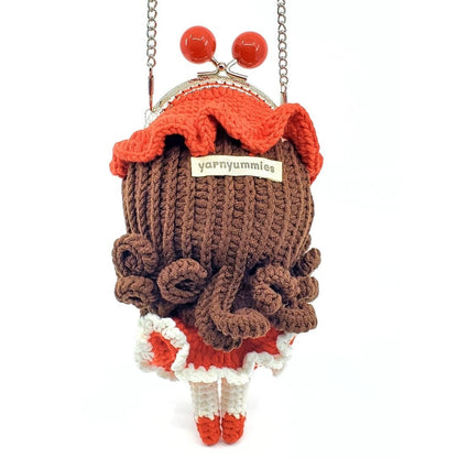 Knitted bag with a brown jead, red top, and red-white skirt on a white background