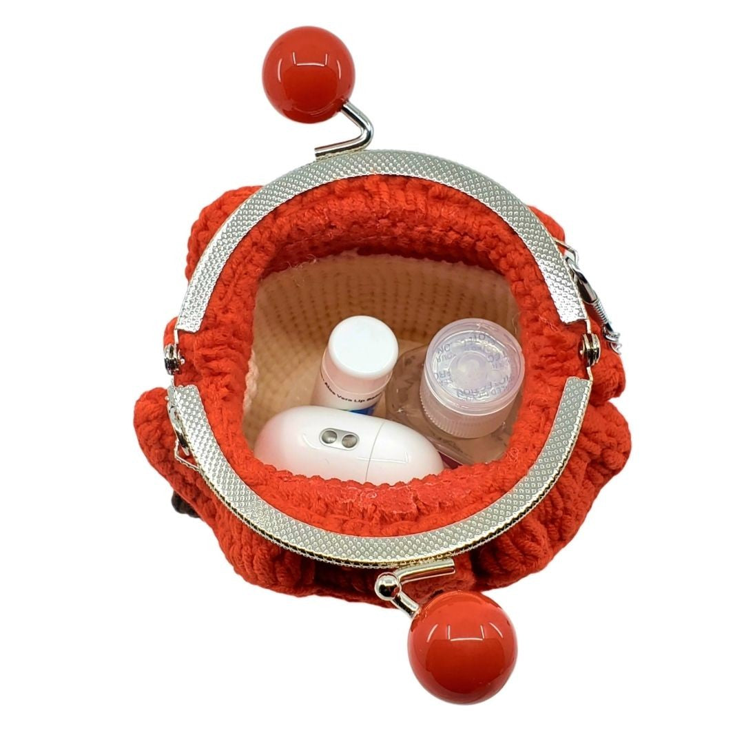 Red textured pouch with a silver clasp containing small bottles on a white background