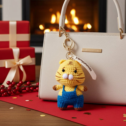 Crocheted tiger keychain on a handbag with Christmas decorations in the background