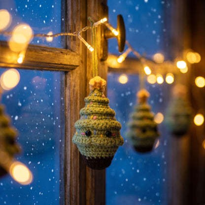 A Handmade crochet Christmas tree ornament by YarnYummies with a small face hangs in front of a window. Warm string lights glow in the background, and a snowy blue window pane is visible behind it.
