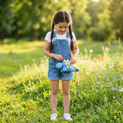 Young girl in a field holding a blue dinosaur designed bag