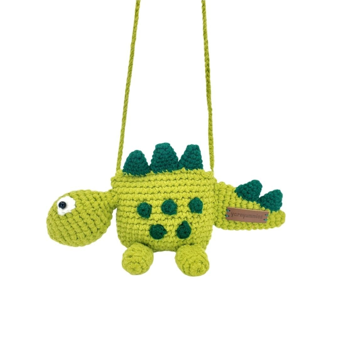 Crocheted dinosaur bag with green spikes on a white background