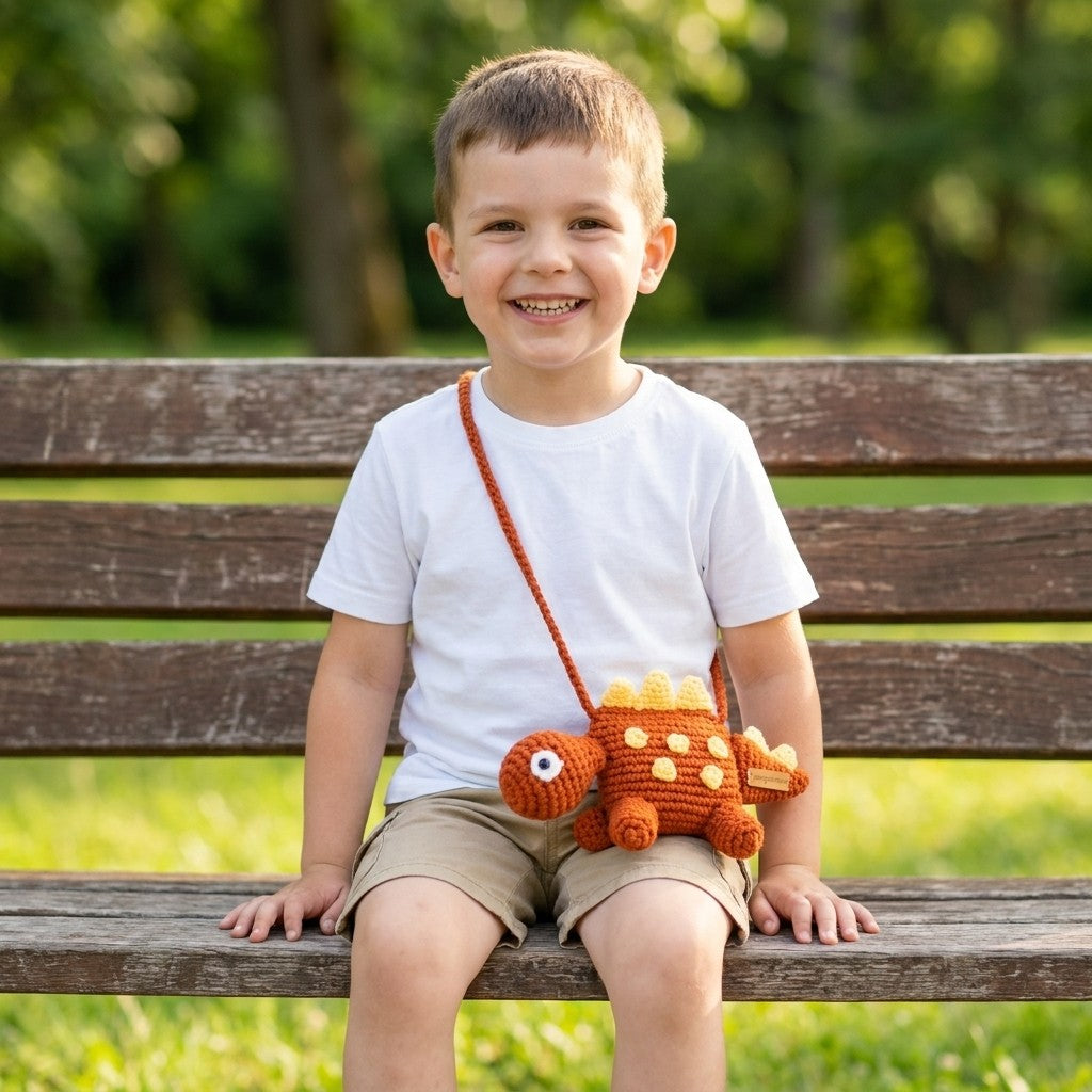 Child sitting on a bench with a dinosaur designed bag, smiling outdoors.