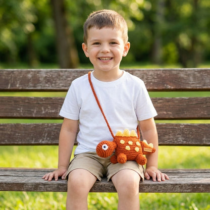 Child sitting on a bench with a dinosaur designed bag, smiling outdoors.