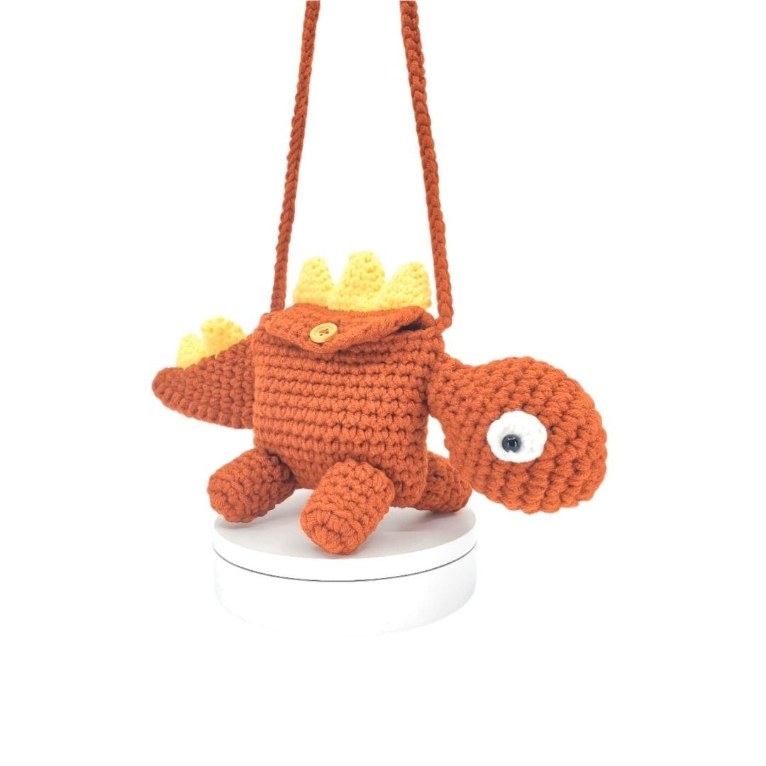 Crocheted red dinosaur bag with a yellow fin on a white background