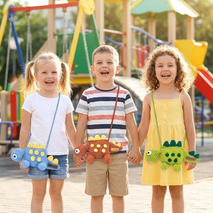 Three children holding hands with dinosaur designed bags in front of a playground.