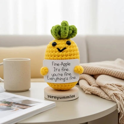 Crocheted pineapple plush decor with a sign on a table, featuring the brand 'yarnyummies'.