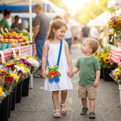 Two children holding hands at an outdoor market with flowers and fruits in the background and girl wearing crossbody bag with colorful crocheted frog design
