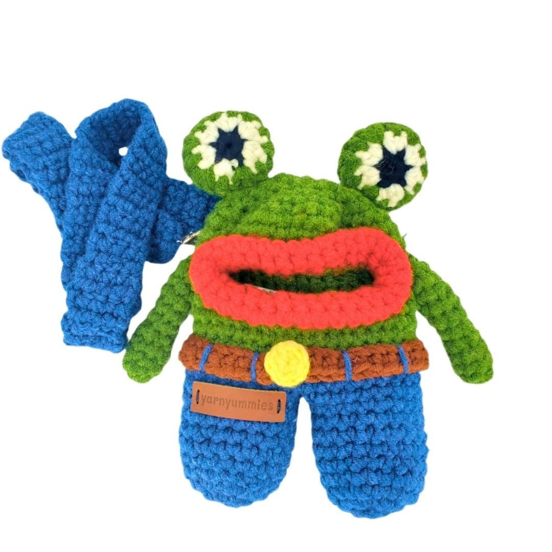 Crocheted frog bag with a blue strap on a white background