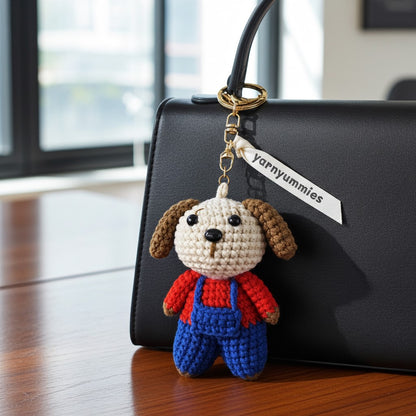 Crocheted dog keychain with a 'Yarnyummies' tag attached to a black handbag.