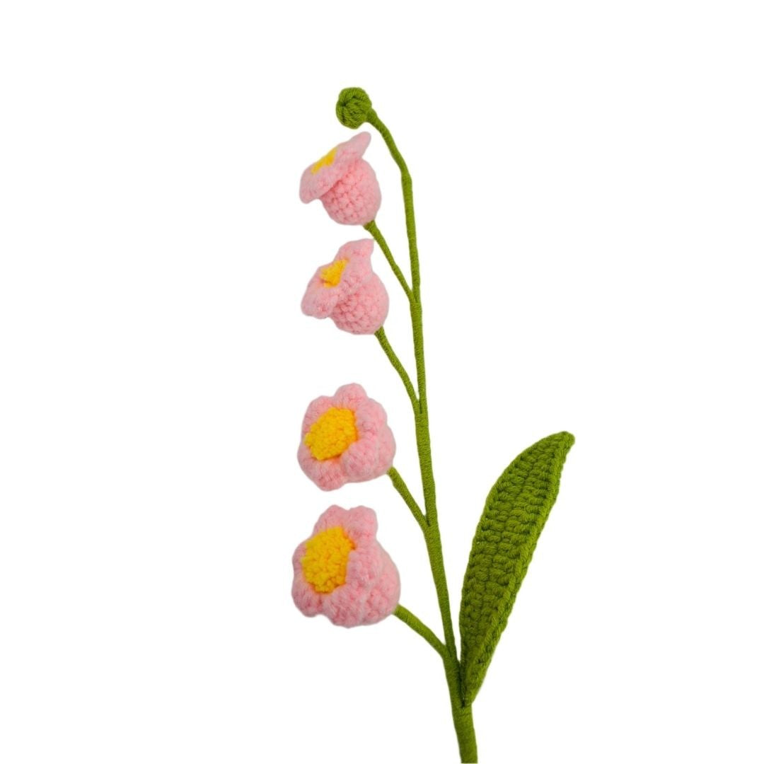 Knitted pink flowers with green stems and leaves on a white background