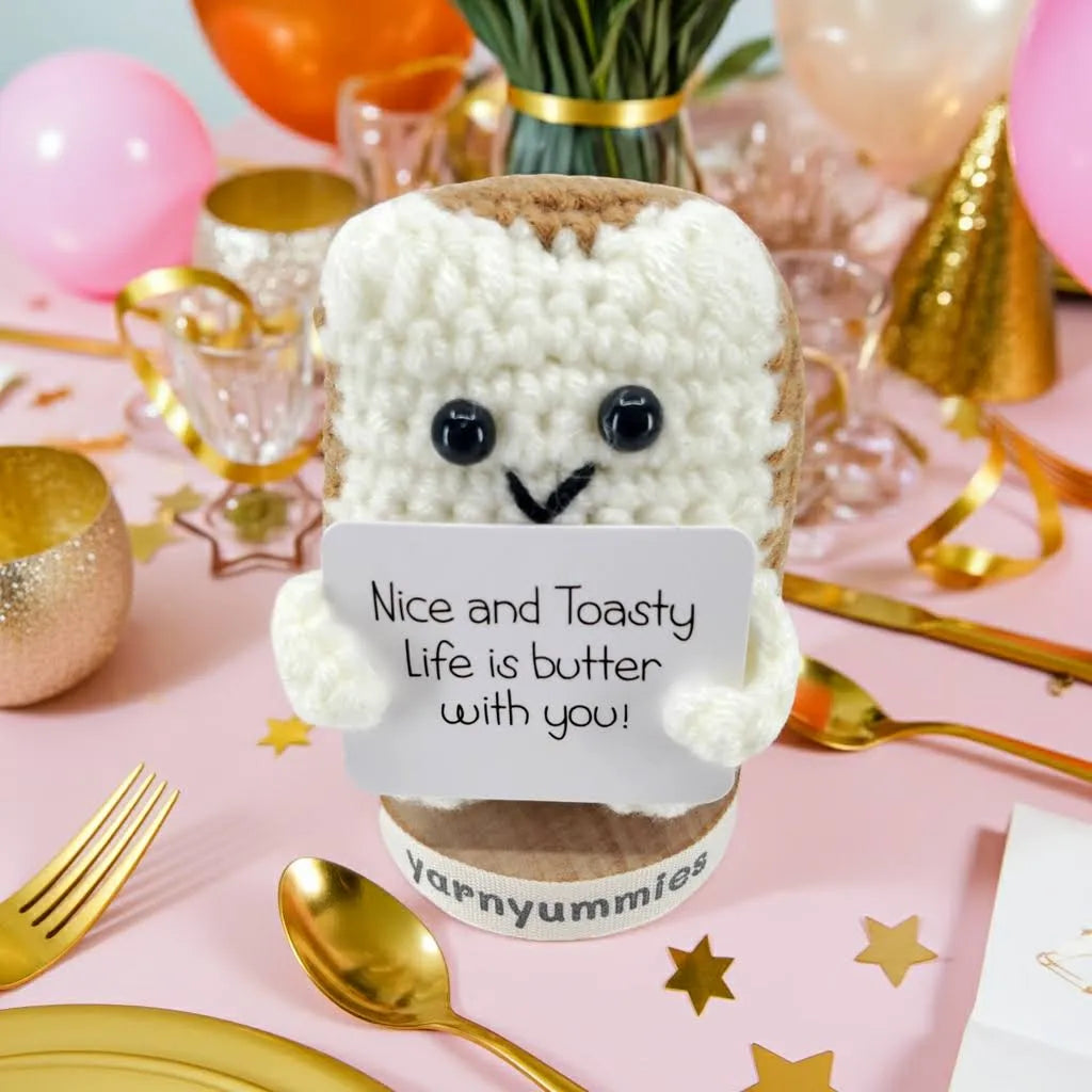 White fluffy toy with a sign on a pink tablecloth with gold utensils and balloons