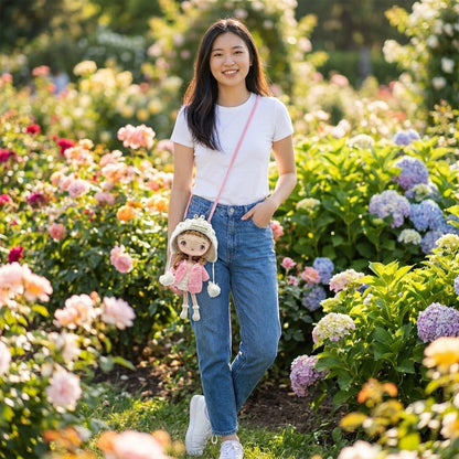 Woman carrying a crossbody doll bag in a garden with flowers