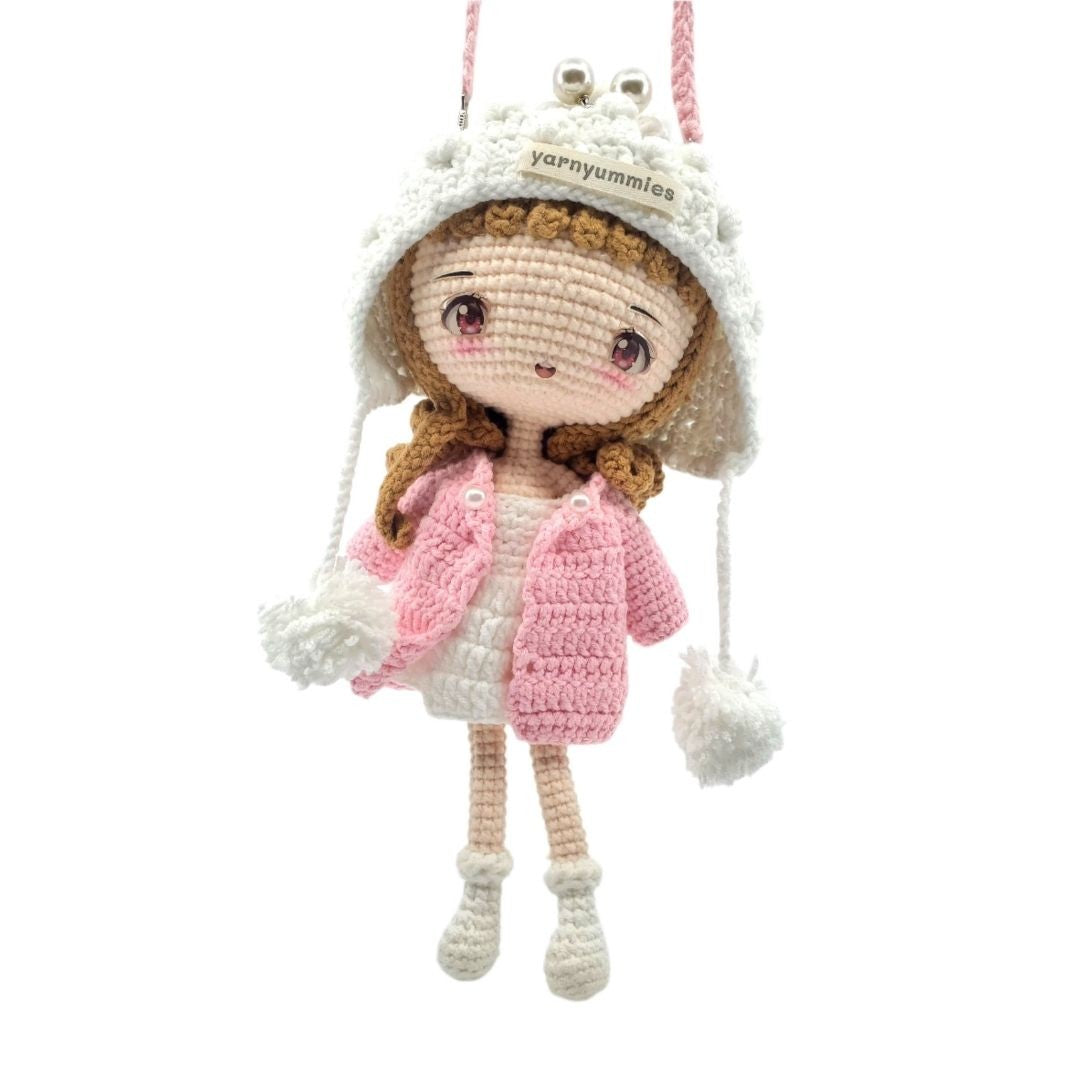 Crocheted doll with a pink coat and white hat on a white background