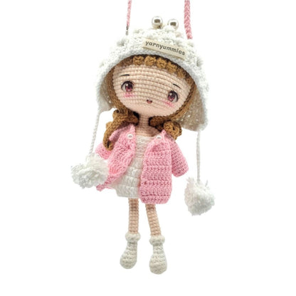 Crocheted doll with a pink coat and white hat on a white background