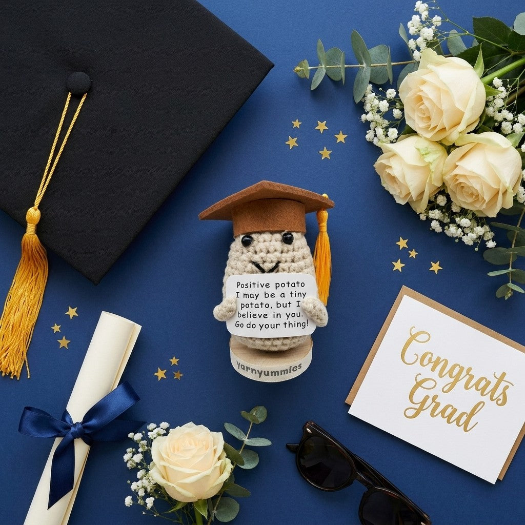 Graduation-themed items including a crocheted positive potato character plush, diploma, and flowers on a blue background.