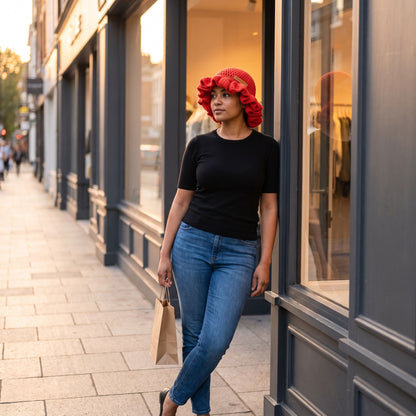 Woman wearing a red handmade crochet ruffled brim bucket hat by YarnYummies while shopping on a city sidewalk at golden hour