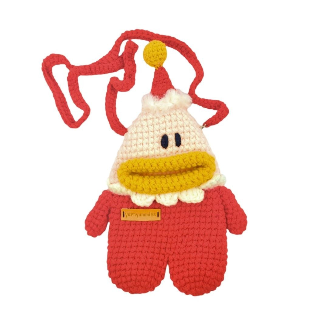 Crocheted santa character with red outfit, yellow scarf, and white hat on a white background