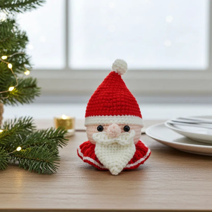 Crocheted Santa Claus figure on a table with Christmas decorations