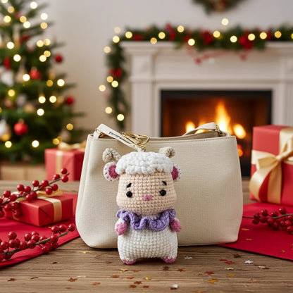 Small crocheted sheep toy in front of a beige handbag with a Christmas tree and fireplace in the background.