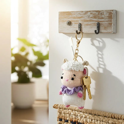 Crocheted keychain with a sheep design hanging on a hook with keys.