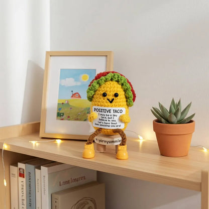 Crocheted taco plush toy on a shelf with books and a plant