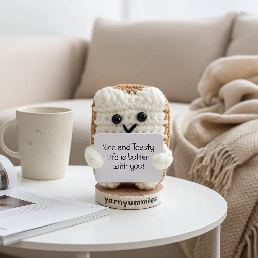 Knitted toast toy with a message card on a table in a cozy living room.
