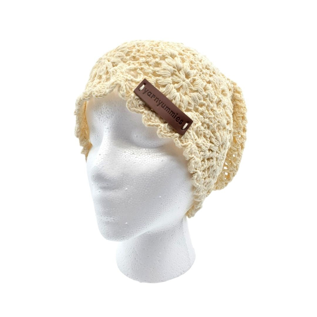 Beige knitted headband on a mannequin head with a visible brand tag against a white background