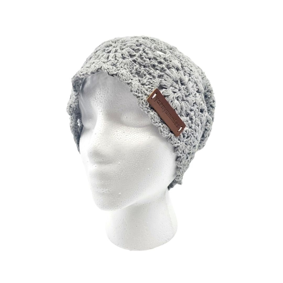Gray knitted beanie with a brown leather tag on a mannequin head against a white background