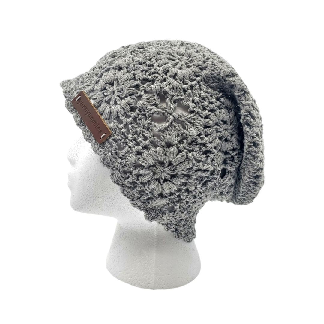 Gray knitted beanie with a brown leather strap on a white mannequin head.