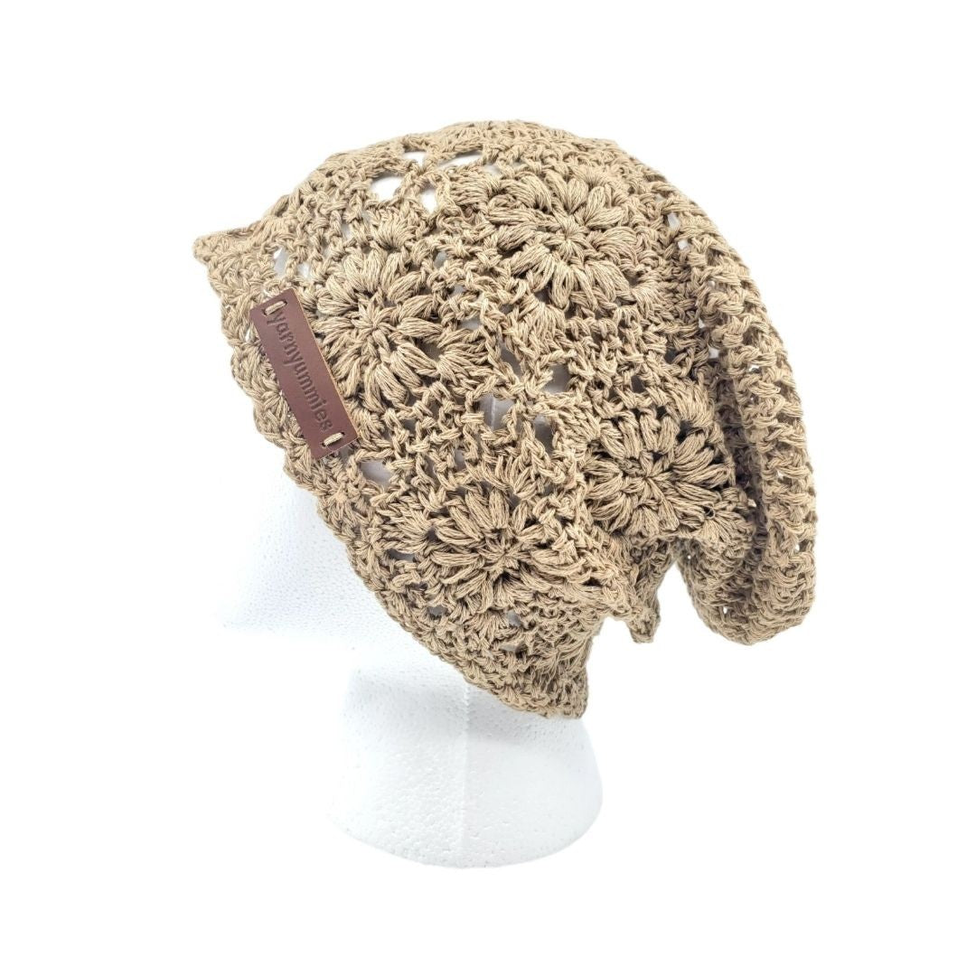 Beige crochet hat with a brown leather patch on a white background