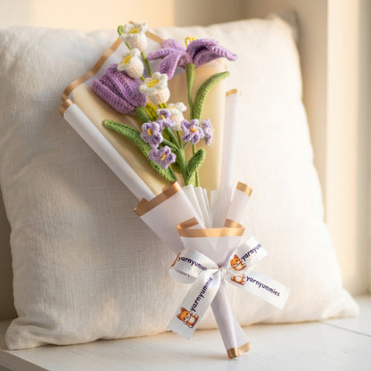 Crocheted purple and white flowers with a white ribbon on a light background