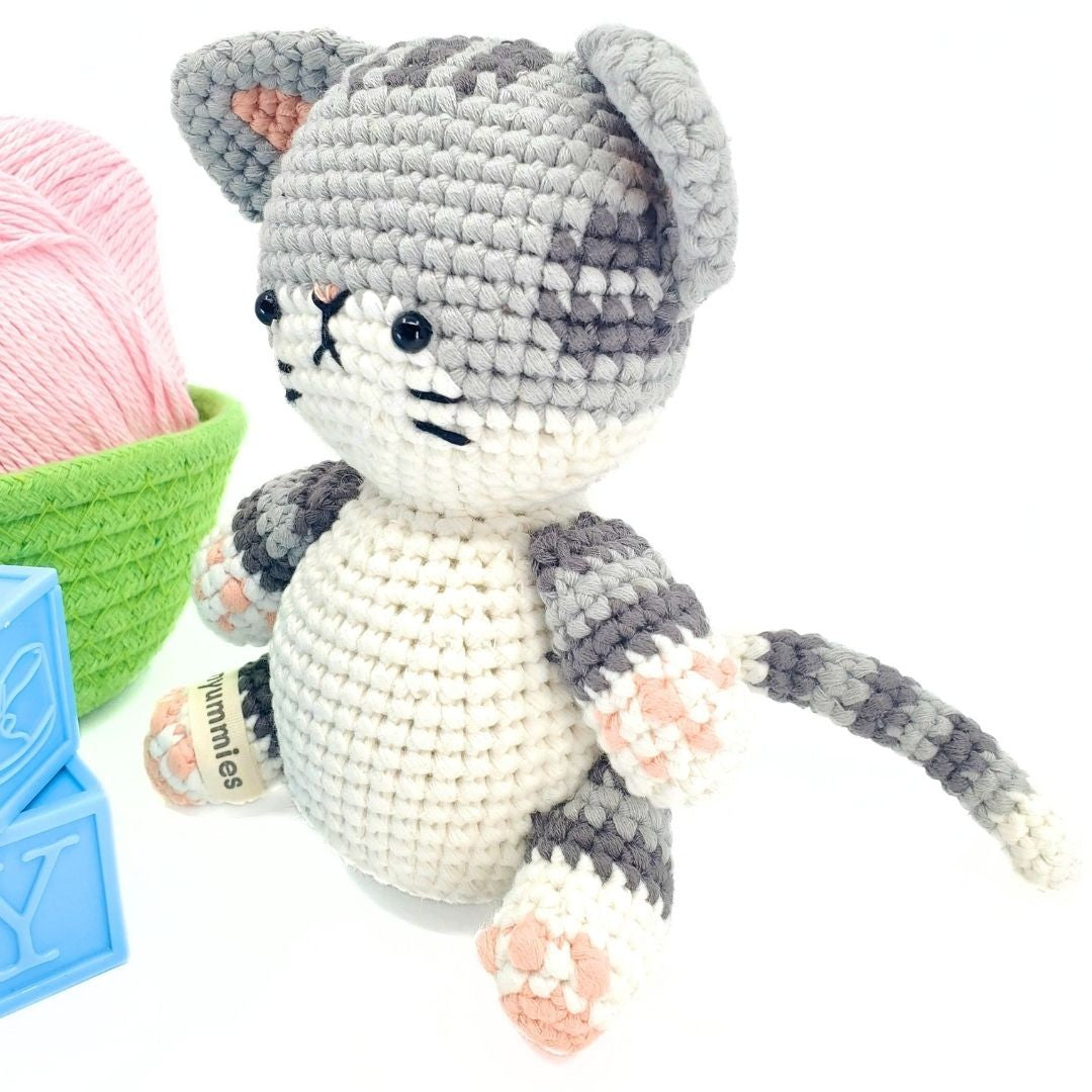 Crocheted cat toy with yarn and tools on a white background