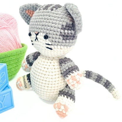 Crocheted cat toy with yarn and tools on a white background