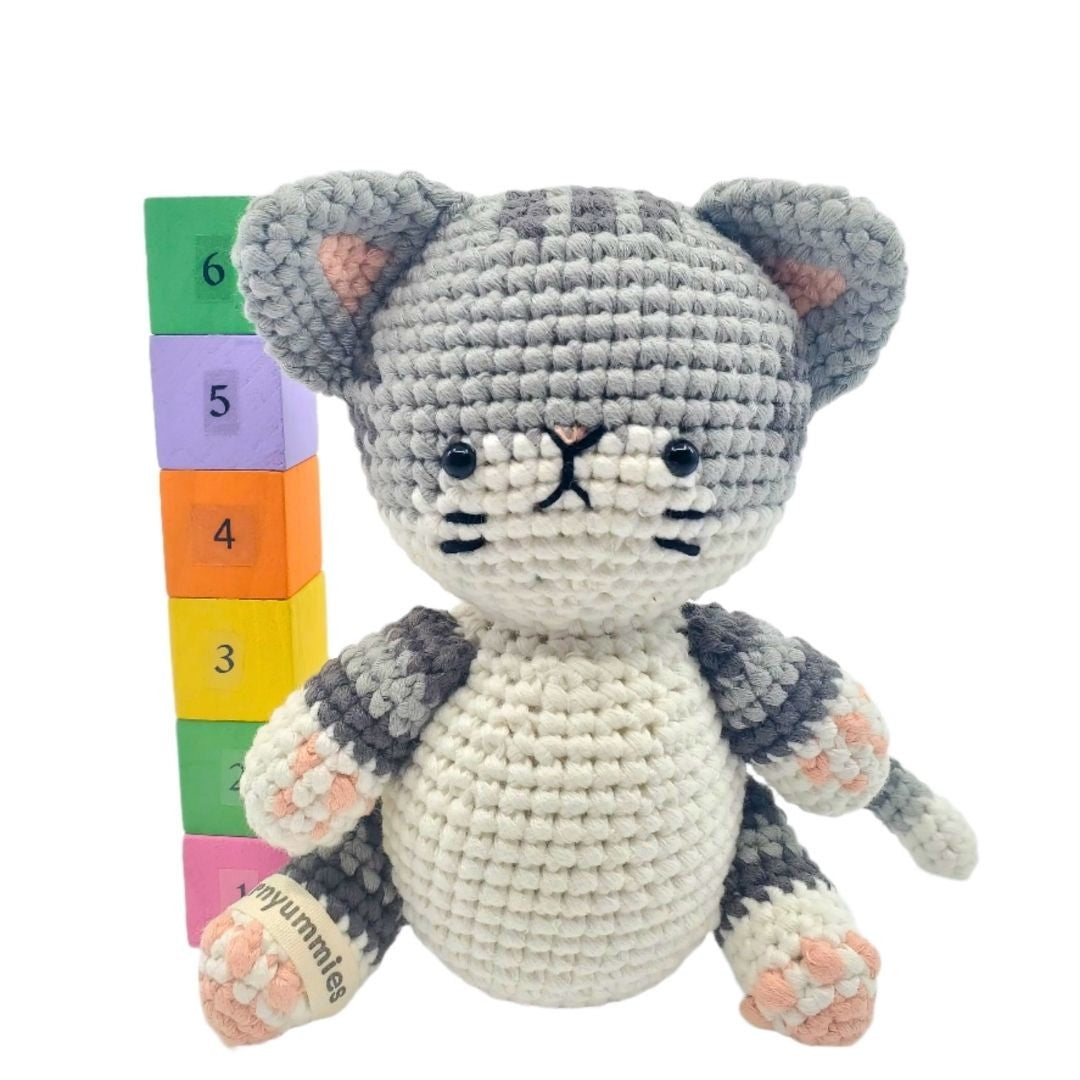 Crocheted cat toy with colorful blocks on a white background