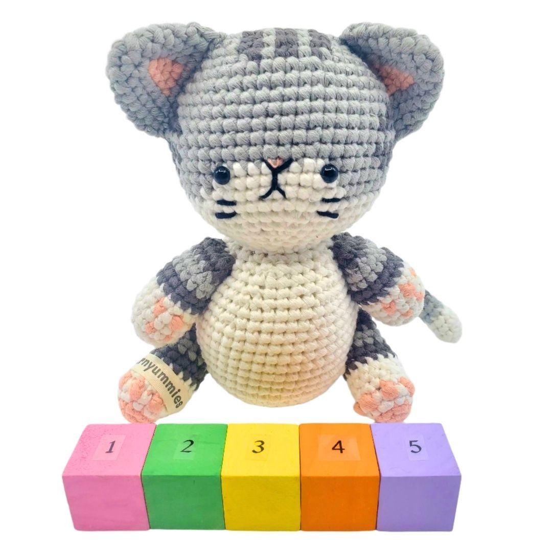 Crocheted cat toy with colorful number blocks on a white background
