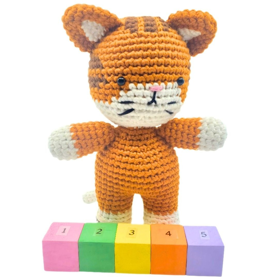 Crocheted tiger toy with colorful blocks on a white background