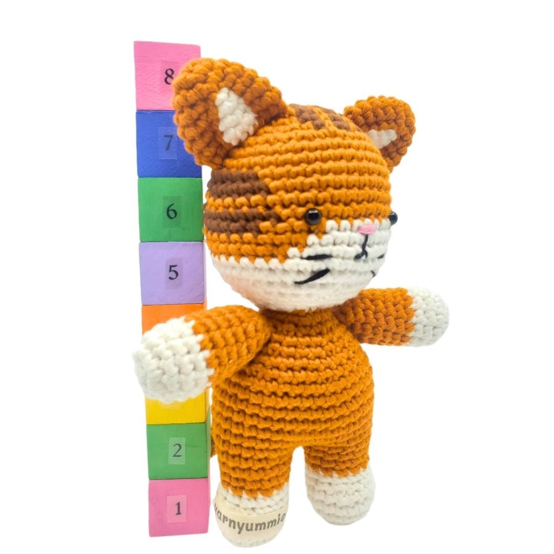 Crocheted fox toy with a colorful height chart on a white background