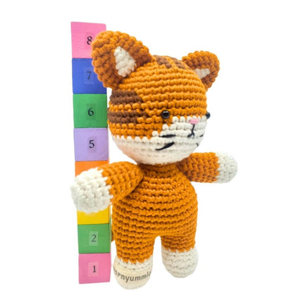 Crocheted fox toy with a colorful height chart on a white background
