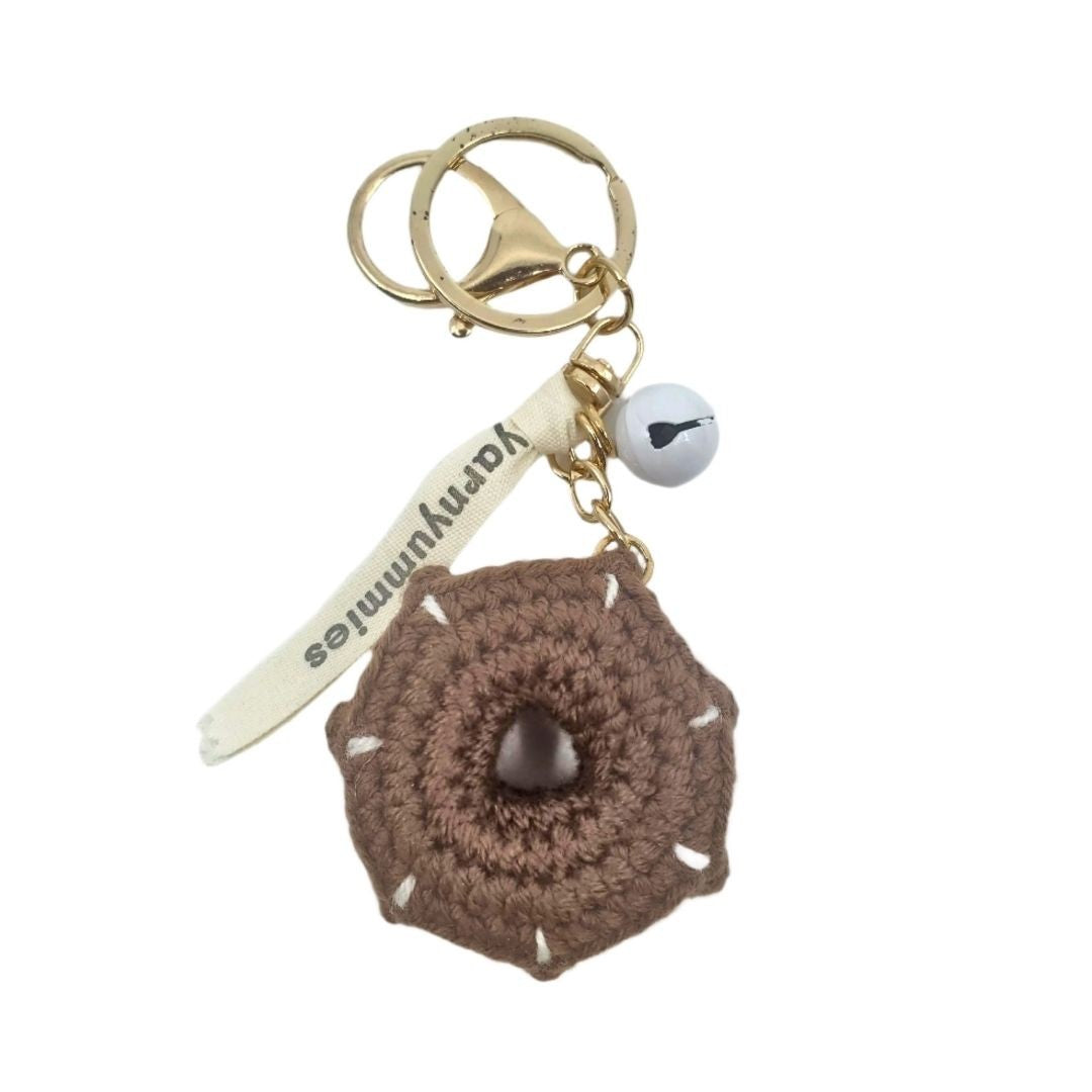 Brown donut-shaped crocheted keychain with a gold ring and white tag on a white background