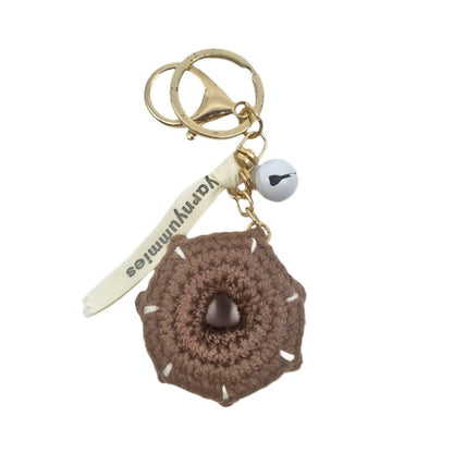 Brown donut-shaped crocheted keychain with a gold ring and white tag on a white background