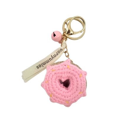 Pink donut-shaped crocheted keychain with a gold ring on a white background